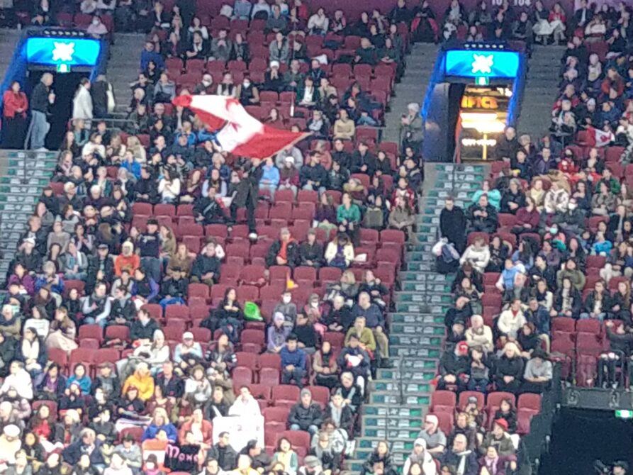 2024WC女子シングルフリー前半グループ演技中に客席で巨大なカナダ国旗を振って応援するナム・グエン選手とキーガン・メッシング