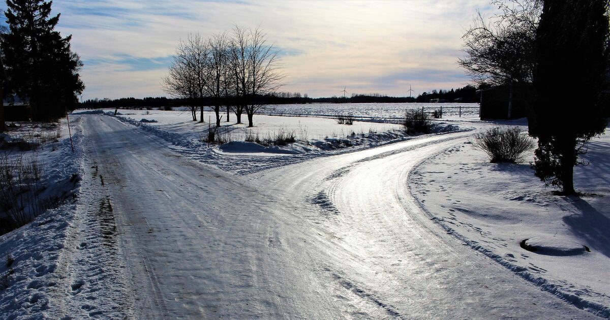 二つのルートに分かれている道、遠くに木々が見え、路面は凍結していて氷が光っている