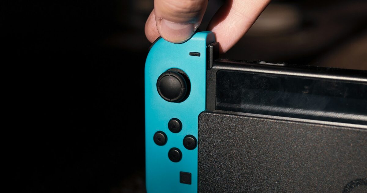 Nintendo Swichの本体から青いジョイコンを取り外そうとする手元アップの写真