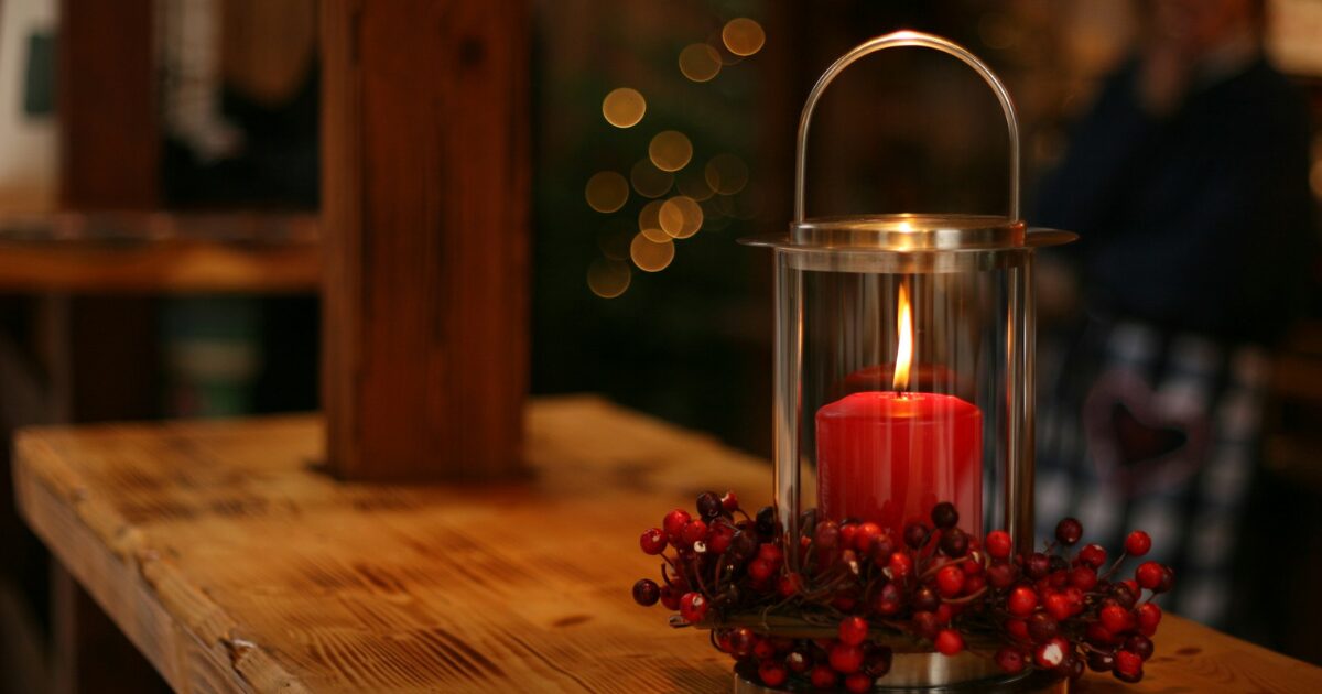 クリスマスツリーを背景にテーブルに赤いキャンドルが燃えている光景