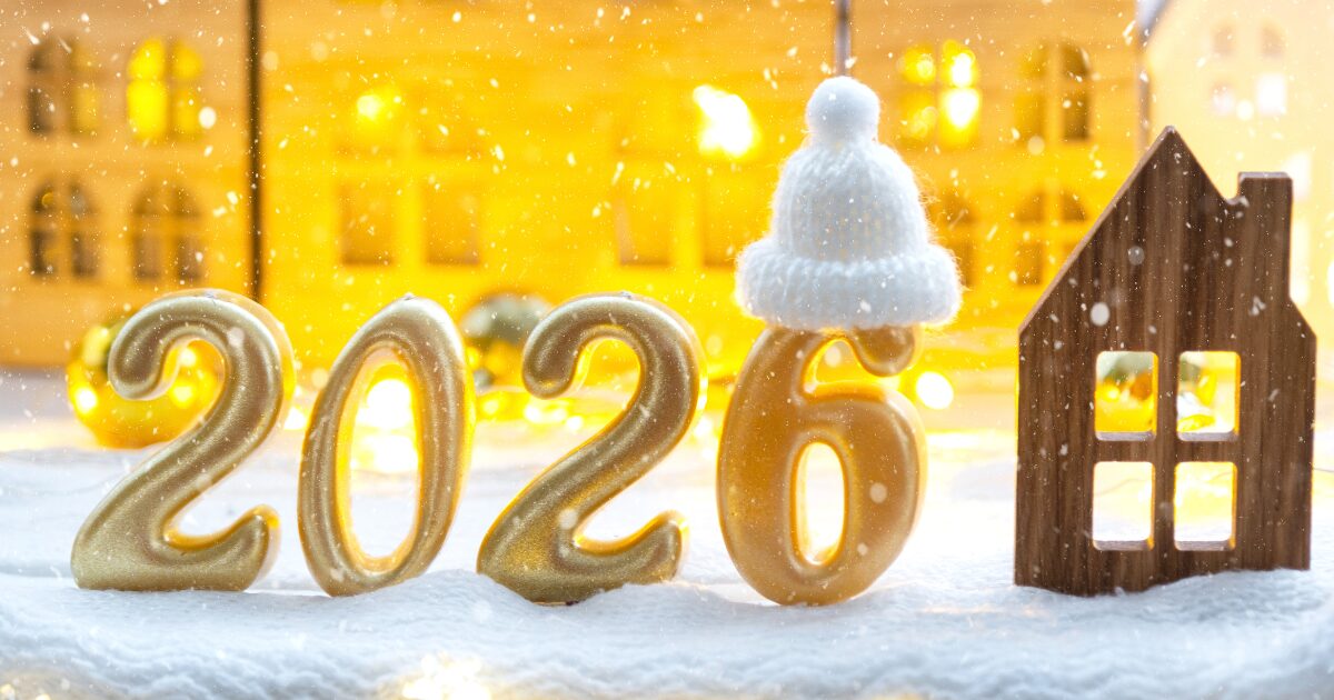 雪景色の中の金色に輝く建物を背景に、金色の2026の文字の写真。6の上には白い帽子がかぶさっている
