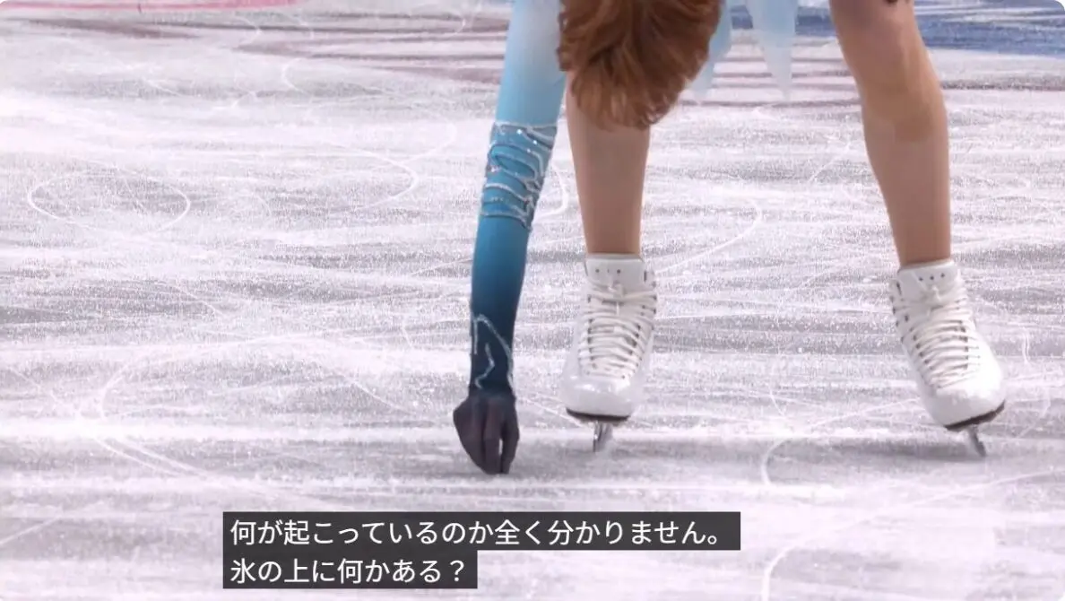 氷上の何かをつまむロパレワ選手の配信画面キャプチャー画像（氷の上に何かがある？の字幕が載っている）