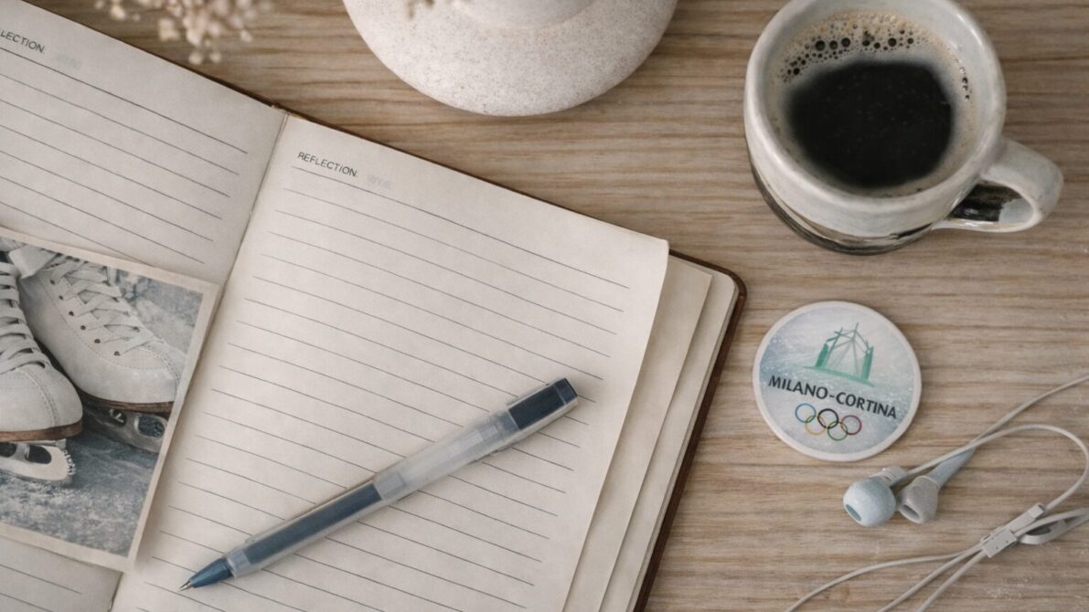 フィギュアスケート靴の写真、コーヒーカップなどが置かれた机の上にノートとペンが広げられている写真
